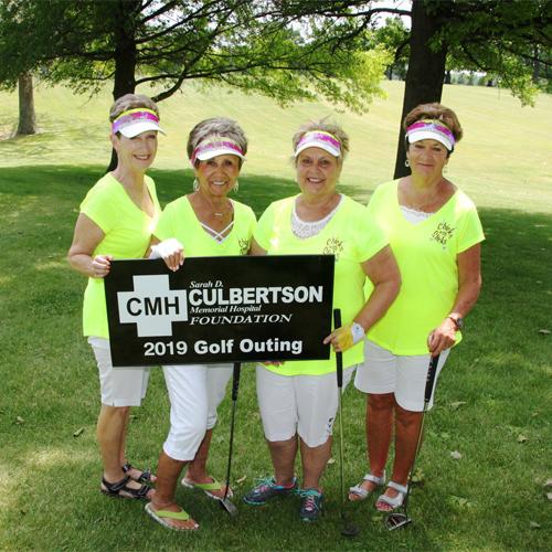 Women out golfing standing next to eachother holding a Culbertson Memorial Hospital Sign