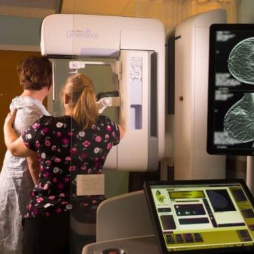 Imaging technician assisting patient in receiving chest x-rays