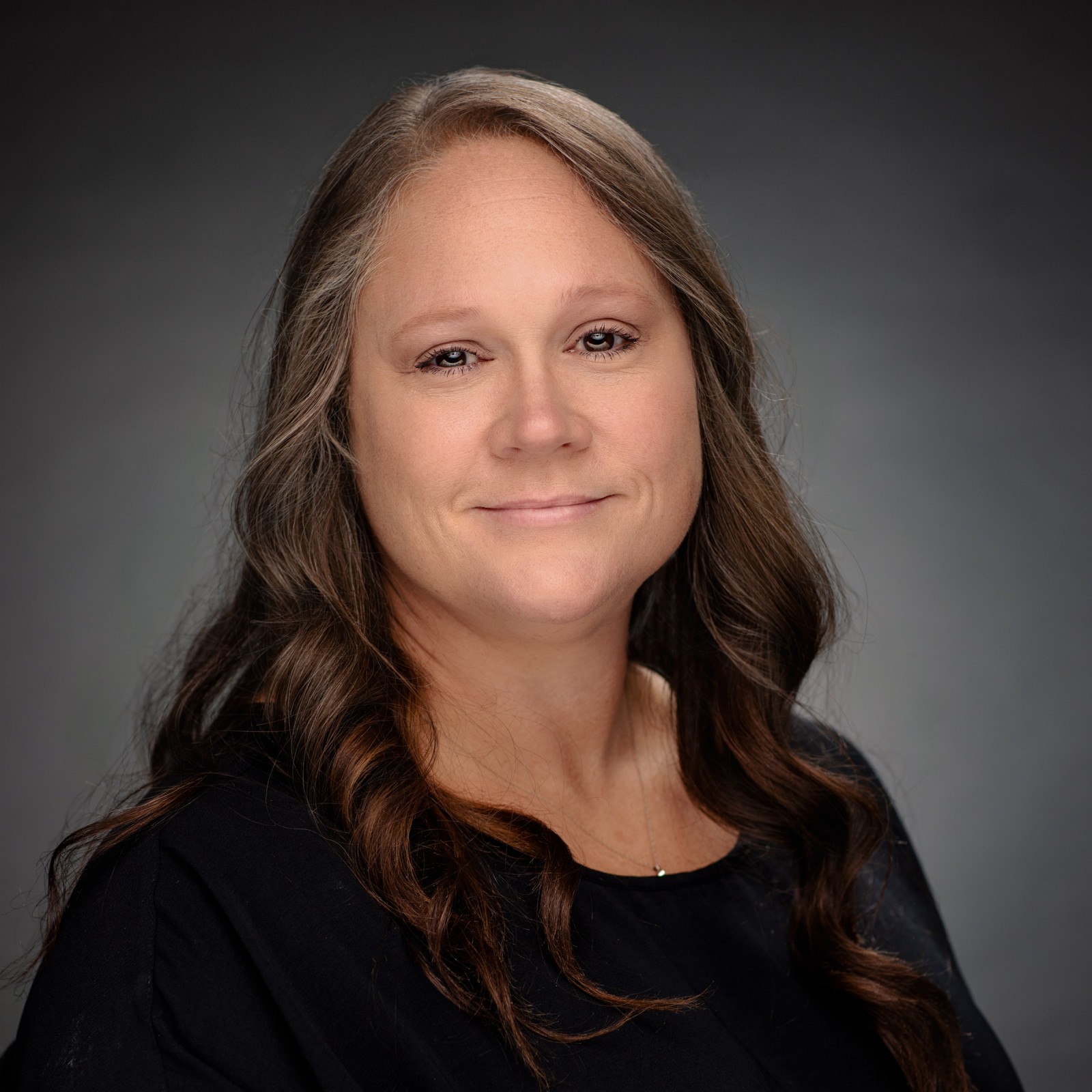 Photo of Patient Access Supervisor with long brown hair and a black shirt.